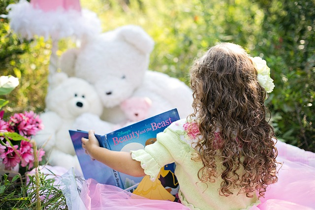 Young Girl Sitting Outdoors Reading a Book to Her Teddy Bears